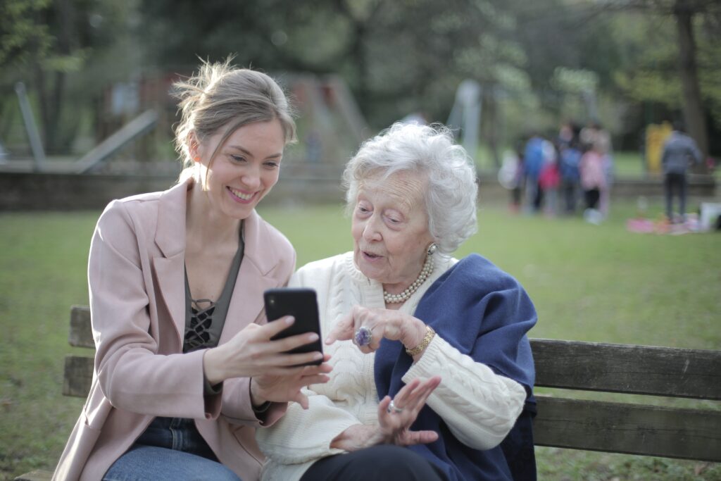 Dos mujeres en un banco de un parque mirando el móvil.